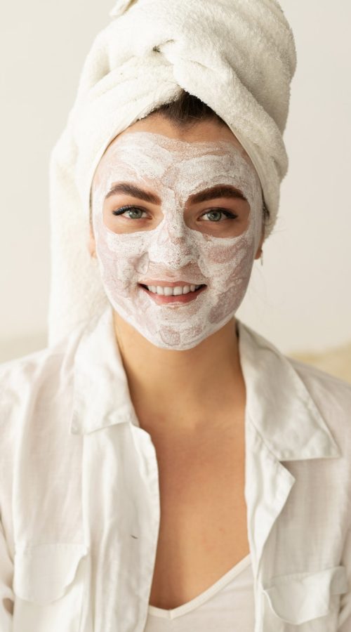 Beautiful woman applying face mask